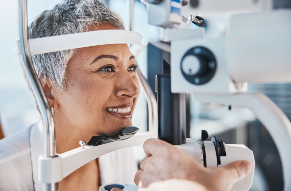 A senior woman smiling during a medical eye exam while an ophthalmologist examines her eyes.