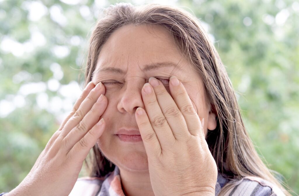 A close-up of a patient holding their hands up to their closed eyes, visibly distressed due to their vision suddenly going black.