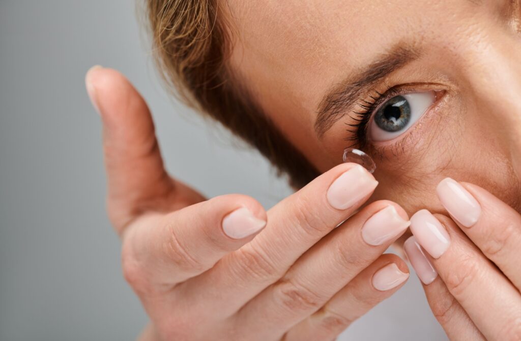 A close up of a person inserting a contact lens into their eye.
