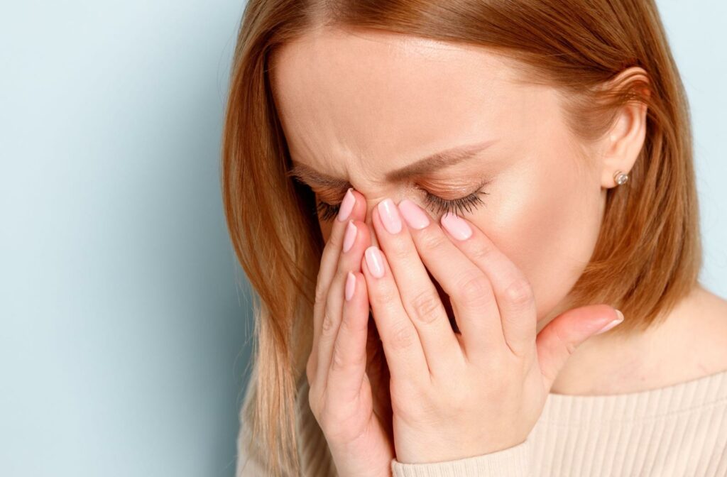 A close up of a person holding their eyes due to excessive watering.